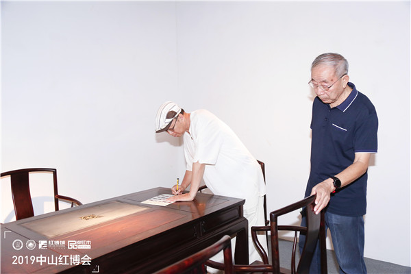 专家评审（左一 教育部教学改革示范专业“家具设计与制造”专业带头人彭亮；右一 中山红木家具工程技术研究开发中心高级顾问曹新民）在为国方家居《168茶台（配南官帽椅）6件套》现场评分，并给予高度评价