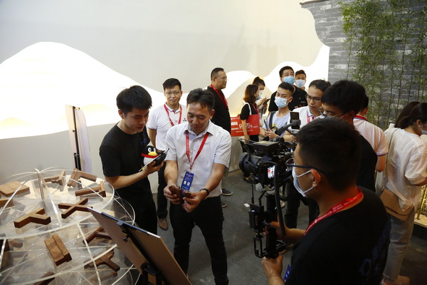 “中式原木整装城市合伙人直播招募会”第一站在国方家居的建博会展位举行，国方家居董事长陈新平（左三）介绍榫卯文化
